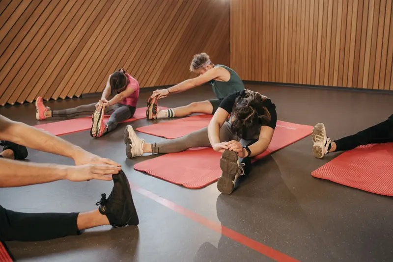 People stretching on exercise mats in an indoor gym during a workout session