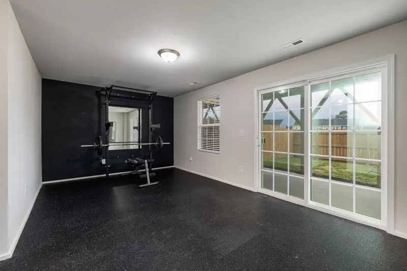 Spacious home gym featuring weightlifting equipment and a mirrored wall