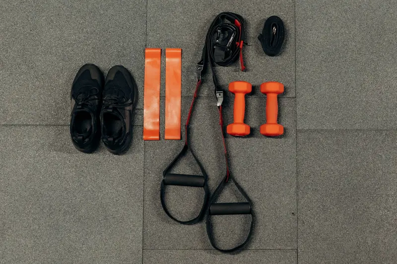 Flat lay of fitness gear including dumbbells, sneakers, and resistance bands for a home workout