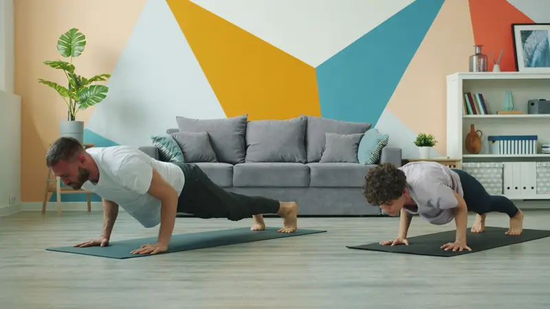 Two adults practicing push-ups in a stylish living room during a daytime workout