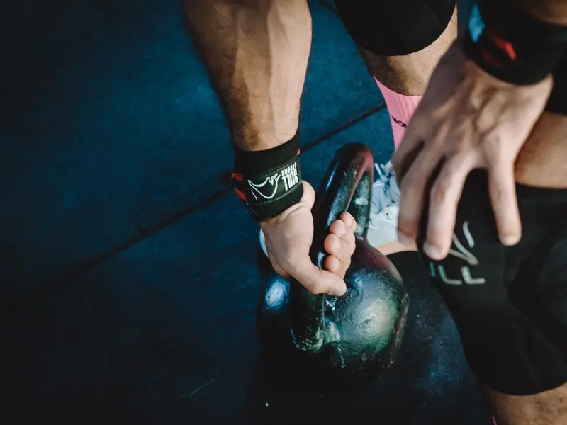 Muscular athlete lifting kettlebell during workout session, showcasing strength and fitness