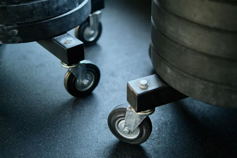 Wheels of gym equipment close-up on a black gym floor, showcasing industrial design