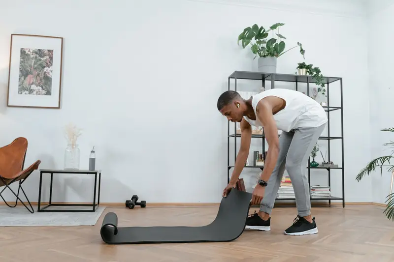 A young man setting up a yoga mat in a stylish home interior for a workout session