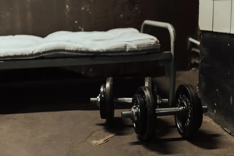 A rustic gym scene featuring dumbbells next to a bed, highlighting home workout possibilities