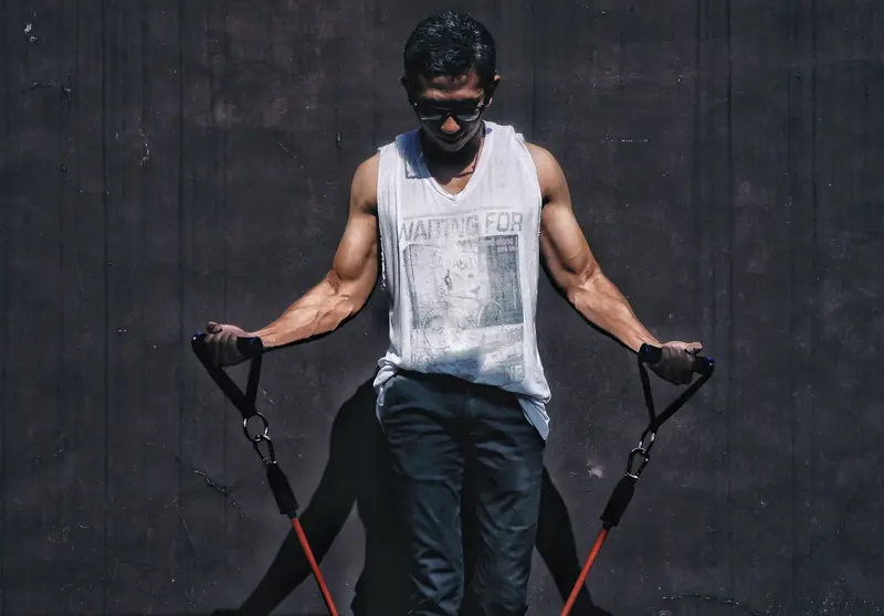 A muscular man using resistance bands outdoors for a fitness workout