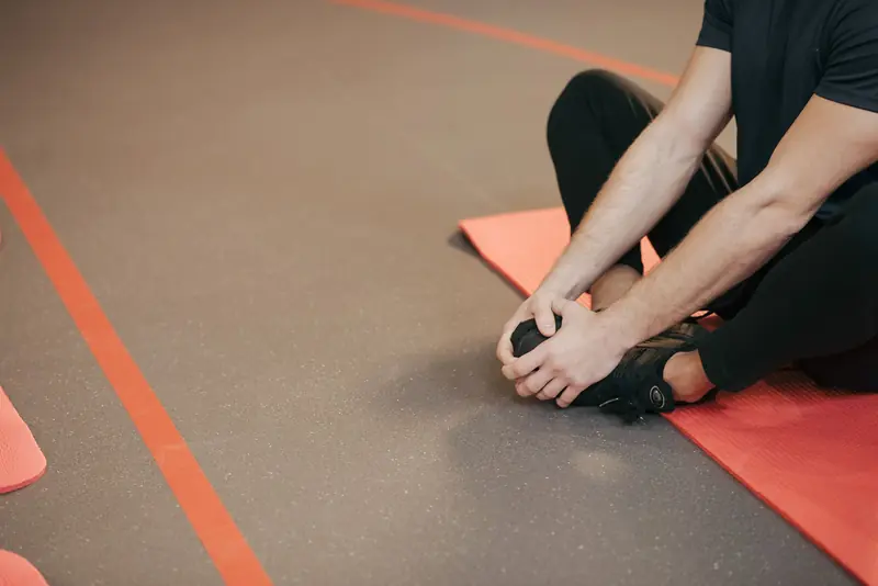 Adult man stretching on a red yoga mat indoors, focusing on flexibility and fitness