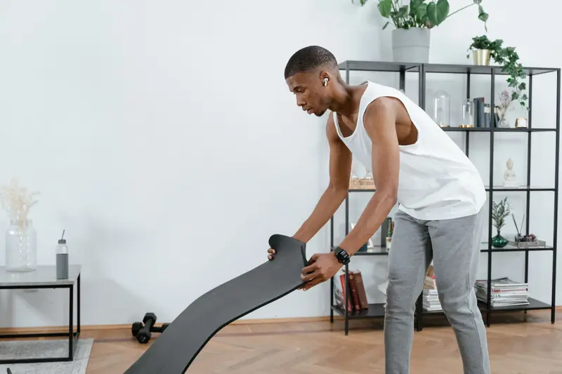 African American man preparing for a workout with yoga mat at home